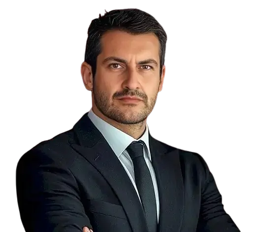 Professional man in a dark suit with white shirt and black tie, arms crossed, looking confidently at the camera.