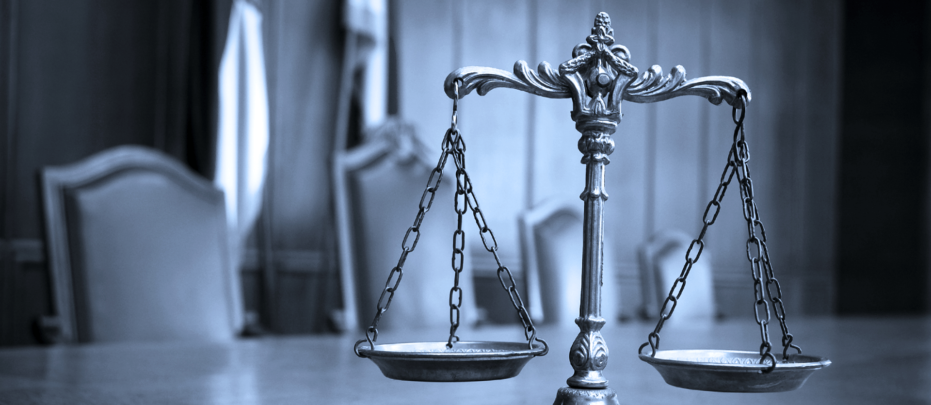 Bronze balance scales in a courtroom, symbolizing justice and fairness.