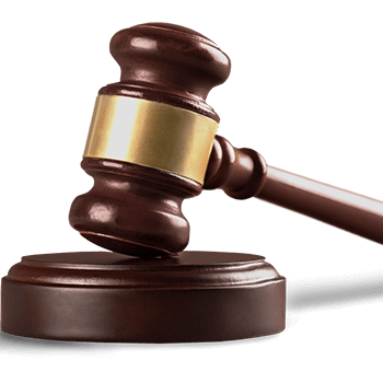 Wooden judge's gavel with brass band resting on a sound block.